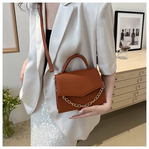 Detail of tan caramel crossbody bag featuring animal texture and gold chain decoration