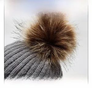 Detail view of the chunky knit grey beanie with a fluffy faux fur pom-pom on top