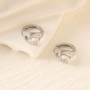 Macro shot of silver heart-shaped zircon earrings with detailed pave stones on silk background