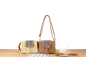 Gros plan de sacs en paille artisanaux avec broderie de perles et pompons colorés