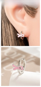 Macro view of silver hoop earrings featuring cute pink enamel bows on a model
