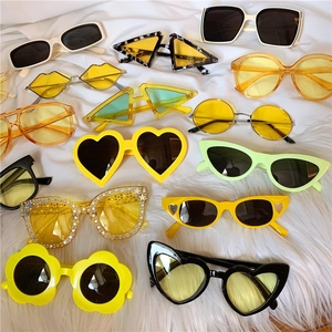 Flat lay of colorful daisy and heart shaped sunglasses on white faux fur background