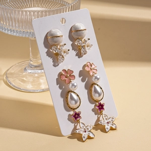 Detail of floral earrings with pink flowers and teardrop pearls on a display card