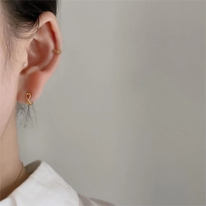 Close-up of minimalist golden infinity hoop earrings and ear cuff on a model ear