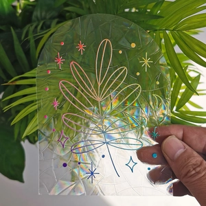 Detail of holographic window film with leaf patterns showing rainbow refraction effect