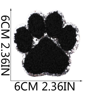 Close-up of black chenille dog paw embroidery patch with silver sequins and 6cm size scale