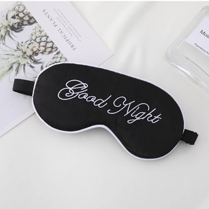 Close-up of black satin sleep mask with Good Night embroidery and adjustable strap
