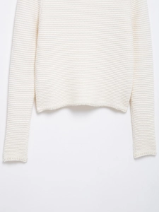 Vue détaillée d'un pull en tricot ivoire avec des perles élégantes sur l'ourlet et poignets