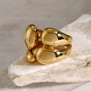 Macro detail of polished 18k gold stacked organic ring on a textured natural stone base