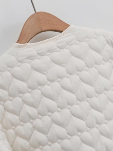 Detail of heart-shaped quilted stitching and round neck collar on white jacket