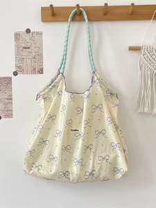 Detail of floral tote bag with bow print and green checkered strap hanging on a hook