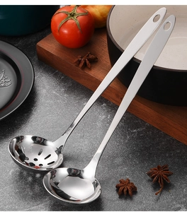 Detailed close-up of stainless steel soup ladle and slotted spoon set on a textured surface