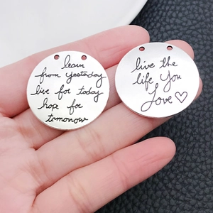 Nahaufnahme von antiken Silberanhängern mit gravierten Motivationssprüchen für DIY-Schmuck