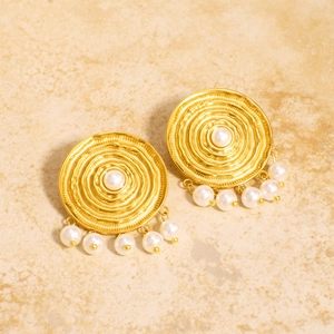 Vintage gold round earrings with pearl fringe and textured disc on stone surface