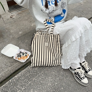Detail of a large capacity striped canvas tote bag in a casual outdoor setting