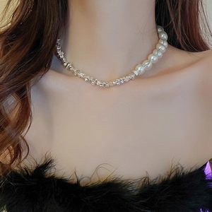 Close-up of irregular silver metal chain with white pearl detail on a model neck