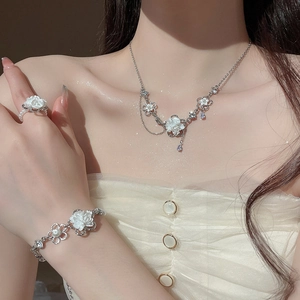 Detail of floral jewelry set with white petals and pearls worn by a model in soft light