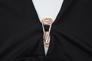 Detail of rose gold shell texture metal buckle on deep V neckline of black dress