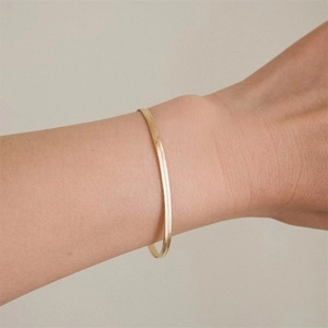 Elegant gold flat snake chain bracelet for women on wrist in minimalist fashion style