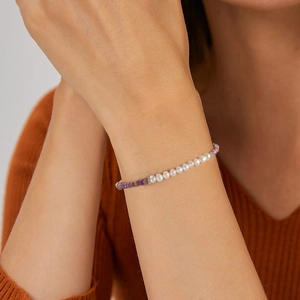 Elegant freshwater pearl and purple stone bracelet with silver beads on a female wrist