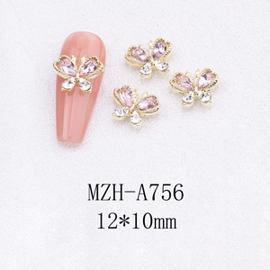 Detailed macro view of gold alloy butterfly nail art charms with pink rhinestones