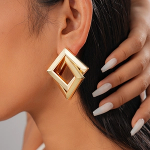 Close-up of geometric interlocking gold diamond earrings with a polished metallic finish