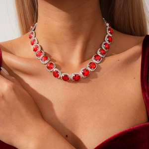 Detailed view of red gemstone necklace with white diamond accents on a velvet outfit
