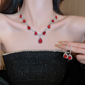 Dettaglio di parure in argento con pietre rosse a goccia indossata da una modella elegante