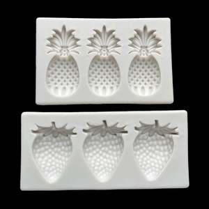 Detailed view of white silicone molds for creating pineapple and strawberry fruit shapes