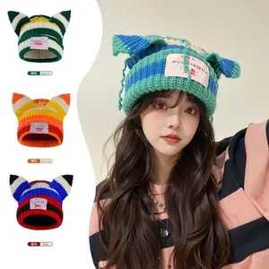 Detail view of colorful striped knit beanies with cat ears and stylish logo patch