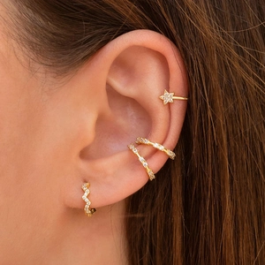 Detail of model wearing gold S925 silver wave earrings and star ear cuffs with crystals