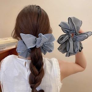Dettaglio di elastici scrunchie in tessuto a quadretti neri e blu con fiocco