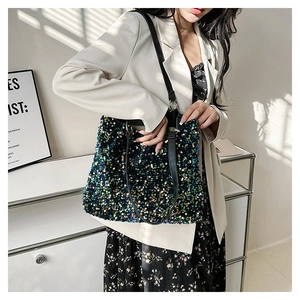Fashionable tote bag with multi-colored sequins and black straps held by a model in a suit