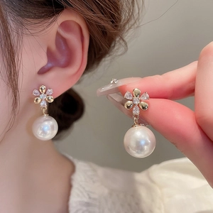 Detail of flower-shaped stud earrings with sparkling crystals and drop pearls