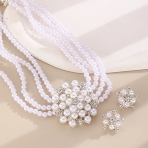 Detailed shot of multi-layer pearl necklace and flower earrings set with rhinestones