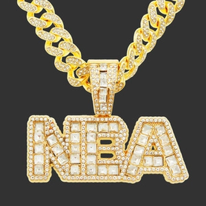 Macro detail of golden NBA pendant with iced out rhinestones on a Cuban chain necklace