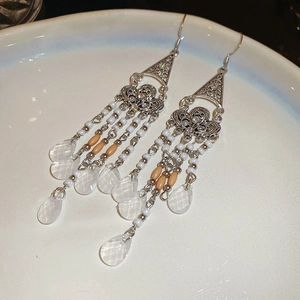 Detail view of bohemian tassel earrings with silver filigree and water drop pendants