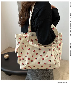 Detailed shot of a white corduroy tote bag with strawberry print and front pocket