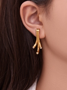 Gros plan de boucles d'oreilles branche dorée géométrique avec zircons incrustés