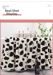 Close-up of thick coral fleece bath towel with black and white cow print texture