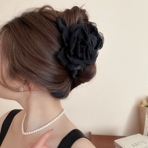 Détail d'une grande pince à cheveux rose en tissu noir sur modèle pour un style élégant