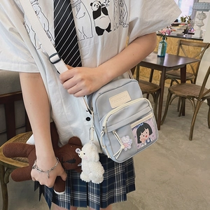 Détail du sac bandoulière en toile bleu clair avec poche transparente et breloques