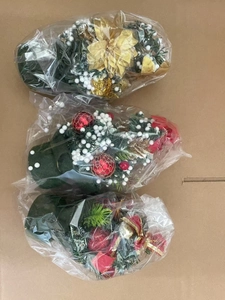 Three Christmas swags with pine cones and ribbons packed in transparent plastic bags