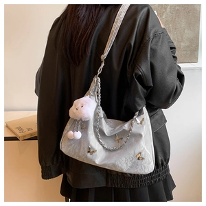 Detail of silver satin tote bag featuring butterfly accent and cloud plush keychain