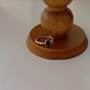 Macro view of vintage silver ring with oval black gemstone on wooden display stand