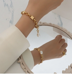 Detail of 18k gold chain bracelet featuring a baroque pearl charm with mirror reflection