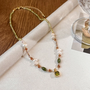 Detail view of the square green crystal pendant and assorted pearls on 18k gold plated chain