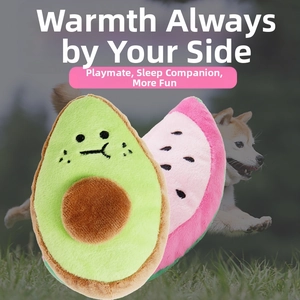 Close-up of plush avocado and watermelon squeaky dog toys on a soft grass background