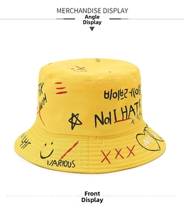 Close-up of yellow cotton bucket hat featuring black street graffiti and heart patterns
