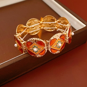 Detailed close-up of vintage gold bracelet with orange enamel stars and pearls